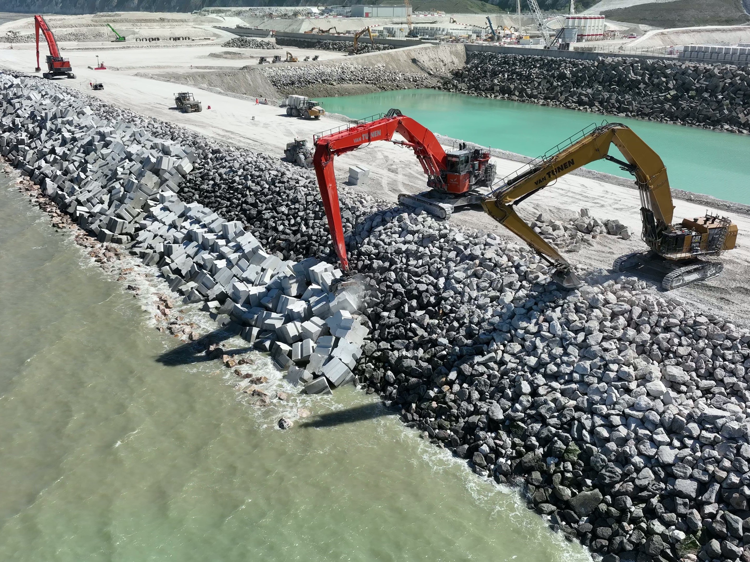 <p>Pose d'enrochements et de BCR sur la digue.</p>
